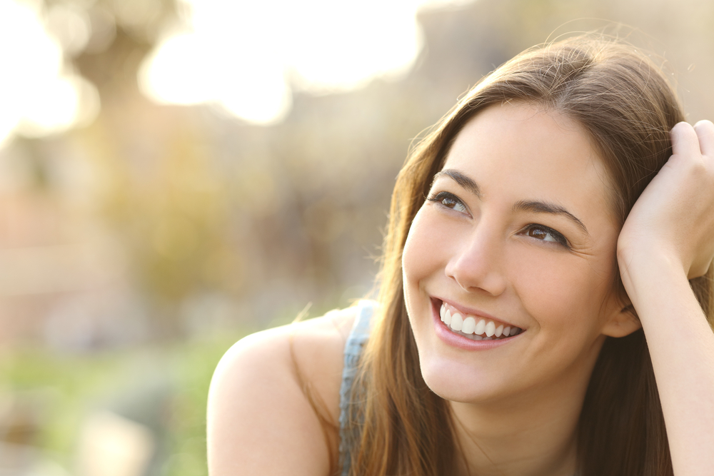 Beautiful Smile After Veneer Treatment - Porcelain Veneers Orange County A confident patient smiles outdoors, showcasing the benefits of porcelain veneers for long-lasting cosmetic improvement - Porcelain Veneers Orange County