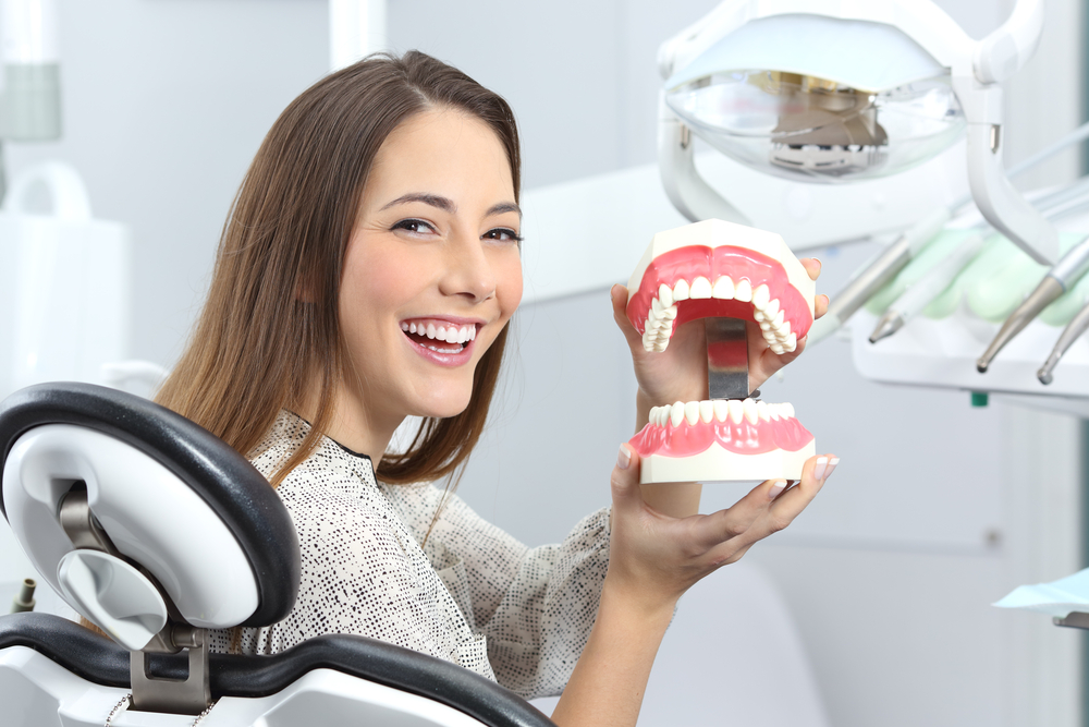 Patient Learning About Smile Treatment Options A smiling patient holds a dental model while discussing cosmetic care and professional whitening solutions for a brighter smile