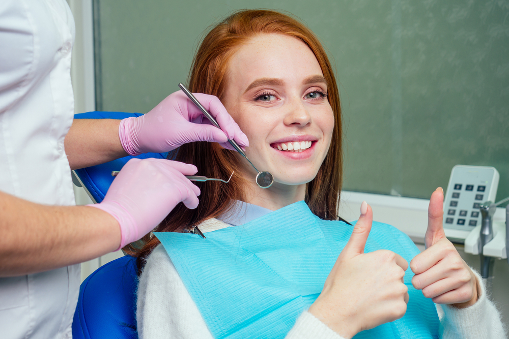 Positive Dental Checkup Results – Invisalign Irvine A smiling patient giving a thumbs up during a successful dental exam and cleaning – Invisalign Irvine