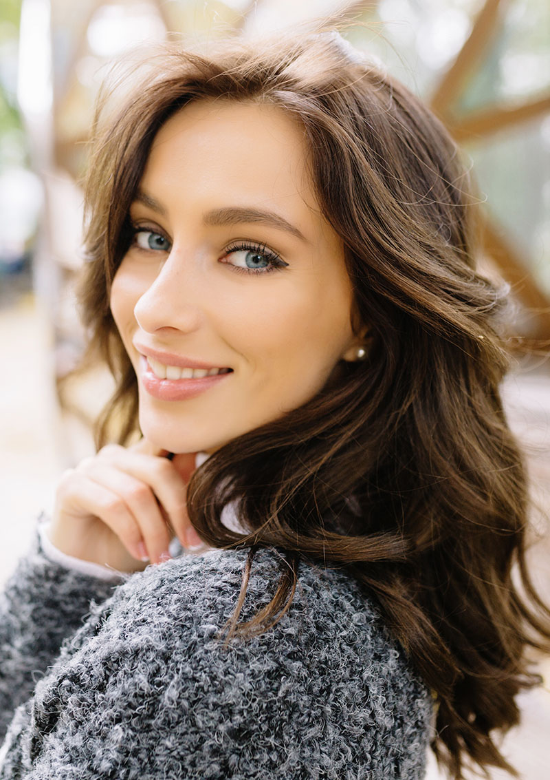 A young woman smiling confidently, representing the benefits of professional cosmetic and preventive dental care – Laguna Hills dentist.